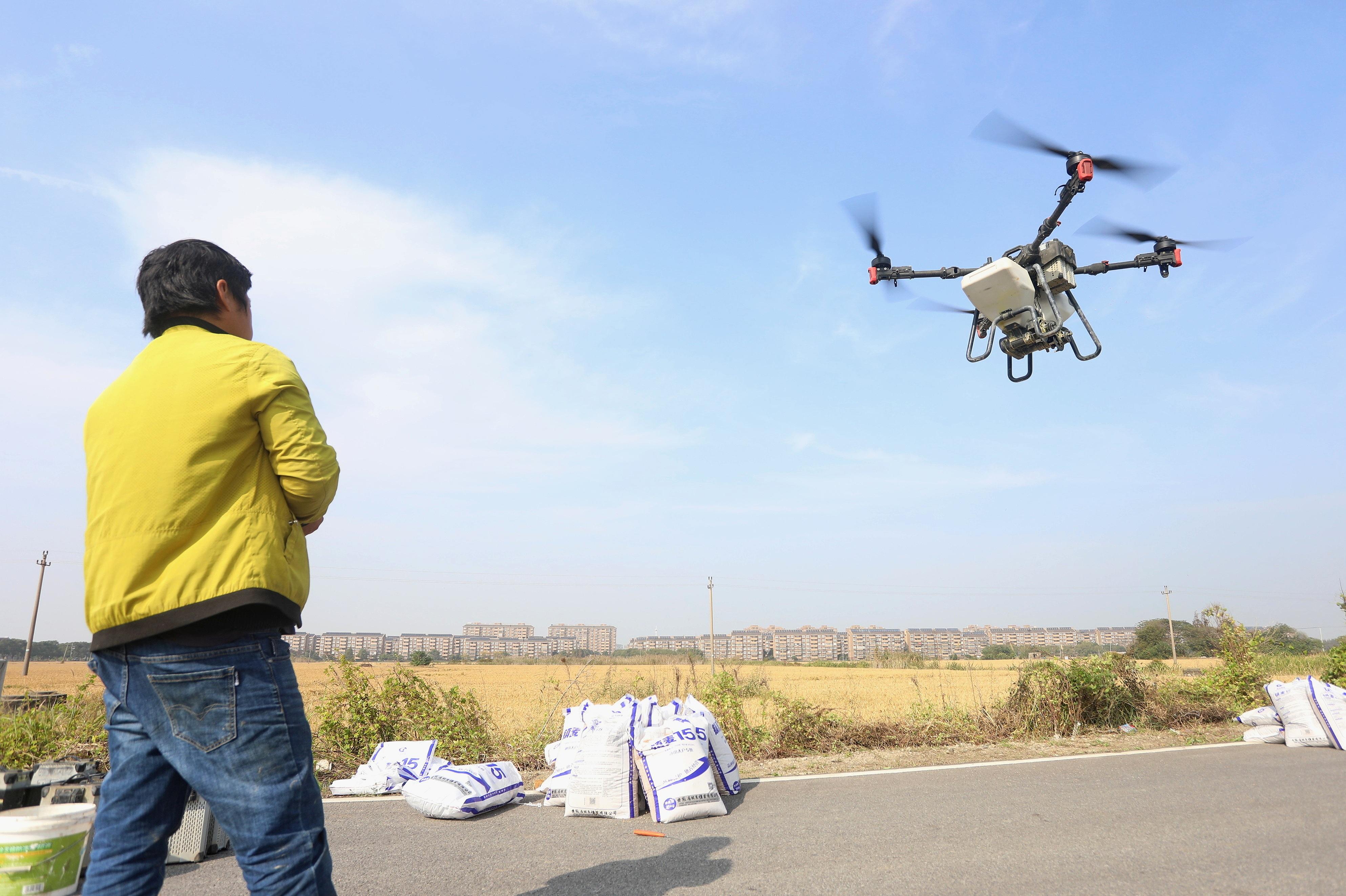 2023年11月15日,浙江嘉兴,南湖区七星街道一处农田里,农民操纵无人机进行冬小麦飞播。